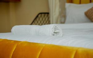 a roll of white towels sitting on a bed at Mustard studio with free WI-FI in Nanyuki +11 photos