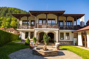 a large house with a balcony and a courtyard at Bashtinata stryaha Guest rooms and Natural pool in Beli Osŭm