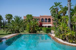 a swimming pool with palm trees and a building at Bab Akoul Atlas - Boutique Hotel & Spa in Aït Namous
