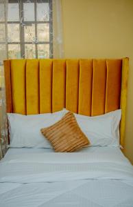 a bed with an orange padded headboard and white pillows at Mustard studio with free WI-FI in Nanyuki
