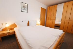 a bedroom with a large white bed with wooden cabinets at Bernstein Mare-Comfort Wohnung 5 in Büsum