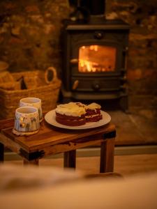 a table with a plate of cake and a stove at Alnwick 2 Bed Cottage Stay, Joe's Cottage in Alnwick