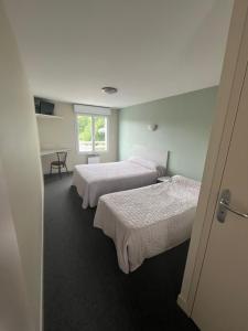 a room with three beds and a window at Hôtel des Voyageurs in Changé