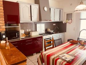 a kitchen with white cabinets and a table and a stove at Les Volets Blancs in Étaples