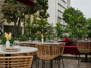 a patio with tables and chairs and a couch at Manto Hotel Lima - MGallery Collection in Lima