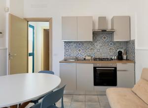 a kitchen with white cabinets and a table and a table and chairs at Veranda sul mare di Donnalucata in Donnalucata