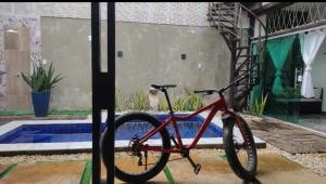 a red bike parked in front of a pool at Casa 3 amores PREÁ, vento, charme, piscina e 2 quartos in Prea