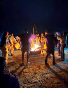 a group of people dancing around a bonfire at night at Unique Luxury Camp in Merzouga