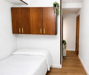 a bedroom with a white bed and wooden cabinets at Letras del Tormes in Salamanca