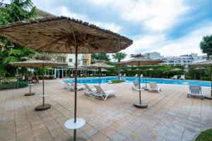 a patio with umbrellas and chairs and a pool at Tranquil condo in Golden Sands in Varna City