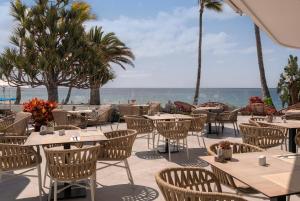 a restaurant with tables and chairs with the ocean in the background at Plus Fariones Suite Hotel in Puerto del Carmen +126 photos