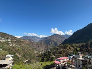 a view of a valley with mountains and houses at Hotel Om Palace in Ukhimath
