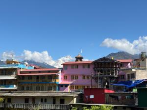 a group of buildings with mountains in the background at Hotel Om Palace in Ukhimath