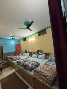 a group of beds in a room with a ceiling at Hotel Om Palace in Ukhimath