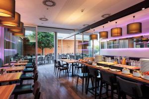 a restaurant with wooden tables and chairs and windows at Hotel Wallern Garni in Wallern an der Trattnach