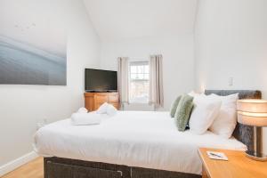 a bedroom with a large white bed and a television at Northern Hideaways, Iona Cottage in Newcastle upon Tyne