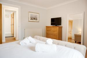 a white bedroom with a bed and a tv at Northern Hideaways, Iona Cottage in Newcastle upon Tyne