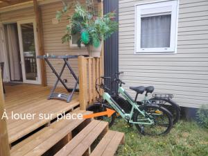 a bike parked on a deck next to a house at MOBIL-HOME "B30" tout confort avec piscine & lave-linge gratuit in Mimizan
