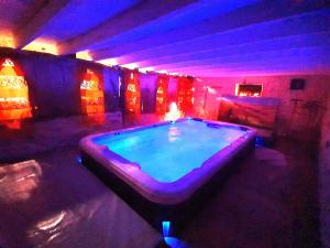 a large swimming pool in a room with purple lights at Les Gîtes de Botte in Duras