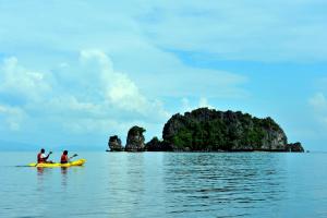 dwoje ludzi na żółtym kajaku w wodzie z wyspą w obiekcie Tanjung Rhu Resort w mieście Tanjung Rhu