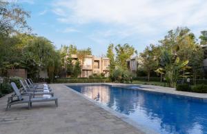 a swimming pool with lounge chairs in front of a house at The Golden Tusk By Ivory Destinations in Rāmnagar