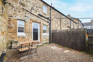 a wooden bench sitting outside of a brick building at Alnwick 2 Bed Cottage Stay, Joe's Cottage in Alnwick