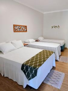 two beds in a room with white walls and wooden floors at Hotel Pousada Riacho da Areia in Águas de Lindoia +291 photos