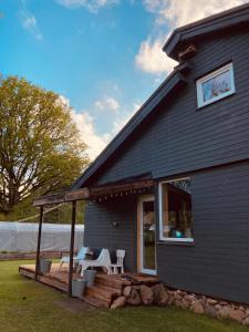 a house with a deck and chairs on it at Pelēkā Māja, forestside getaway house for cosy stays in Myza Brenguli