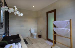 a bathroom with a toilet and a shelf with towels at Sandi Agung Villa in Seminyak