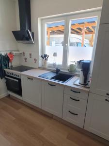 a kitchen with white cabinets and a sink and a window at Ferienwohnung Dreiländereck Gronau in Spechtholzhock