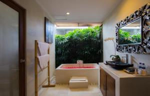 y baño con bañera, lavabo y espejo. en Sandi Agung Villa, en Seminyak