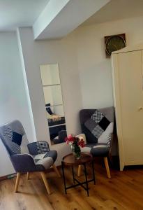 a room with two chairs and a table and a clock at Studio Confort in Château-Chinon