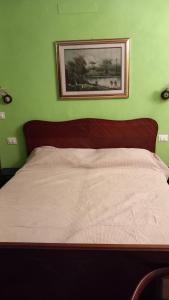 a bed in a green bedroom with a picture on the wall at affittacamere de al vecchio scalo in Isola del Cantone