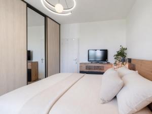a bedroom with a large white bed and a tv at Tatra's View Apartment in Poprad