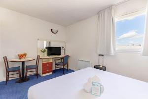a hotel room with a bed and a table with chairs at Appart'City Classic Clermont Ferrand Centre in Clermont-Ferrand