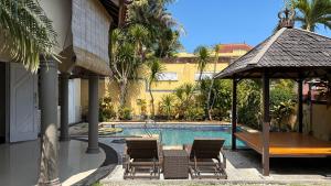 a pool with chairs and a table and a gazebo at The Beverly Hills Bali Villas Resort in Jimbaran