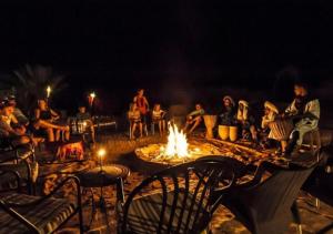 a group of people sitting around a fire pit at night at Sunny Luxury Camp in Merzouga