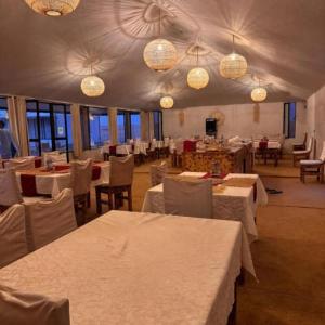 a dining room with tables and chairs and chandeliers at Sunny Luxury Camp in Merzouga