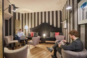 two people sitting in chairs in a hotel room at Hôtel La Parizienne - Proche Montparnasse in Paris