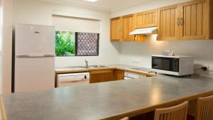 a kitchen with a counter with a microwave and a refrigerator at Boambee Bay Resort in Bonville