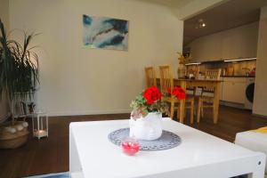 a white table with a vase with red flowers on it at Apple Tree Garden House in Örebro +10 photos