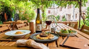 a table with a plate of food and a bottle of wine at Auberge des Salelles - Zarathoustra in Saint-Maurice-dʼIbie