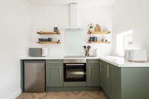 a kitchen with green cabinets and white counter tops at Spacious Beach House Near Promenade & Beach Sleeps 6 in Newbiggin-by-the-Sea