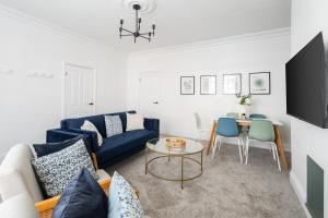 a living room with a blue couch and a table at Spacious Beach House Near Promenade & Beach Sleeps 6 in Newbiggin-by-the-Sea