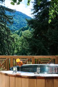 a hot tub with a drink on a wooden deck at Le Parc - Hôtel & Spa in Allevard