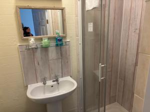 a bathroom with a sink and a shower with a mirror at Weybourne Guest House in Tenby