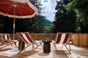 two chairs and a table and an umbrella on a patio at Le Parc - Hôtel & Spa in Allevard