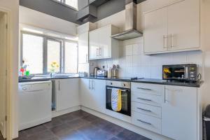 a white kitchen with white cabinets and a microwave at Finest Retreats - Seabreeze, Rhos On Sea in Rhos-on-Sea
