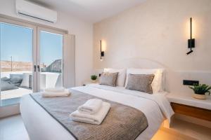 a white bedroom with a large bed with towels on it at Serenity Collection Suites in Karterados +75 photos