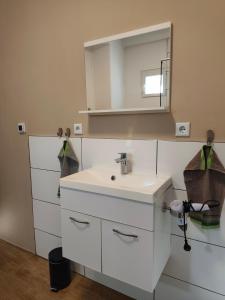 a white bathroom with a sink and a mirror at Apartment Linde Otzenhausen in Nonnweiler +5 photos